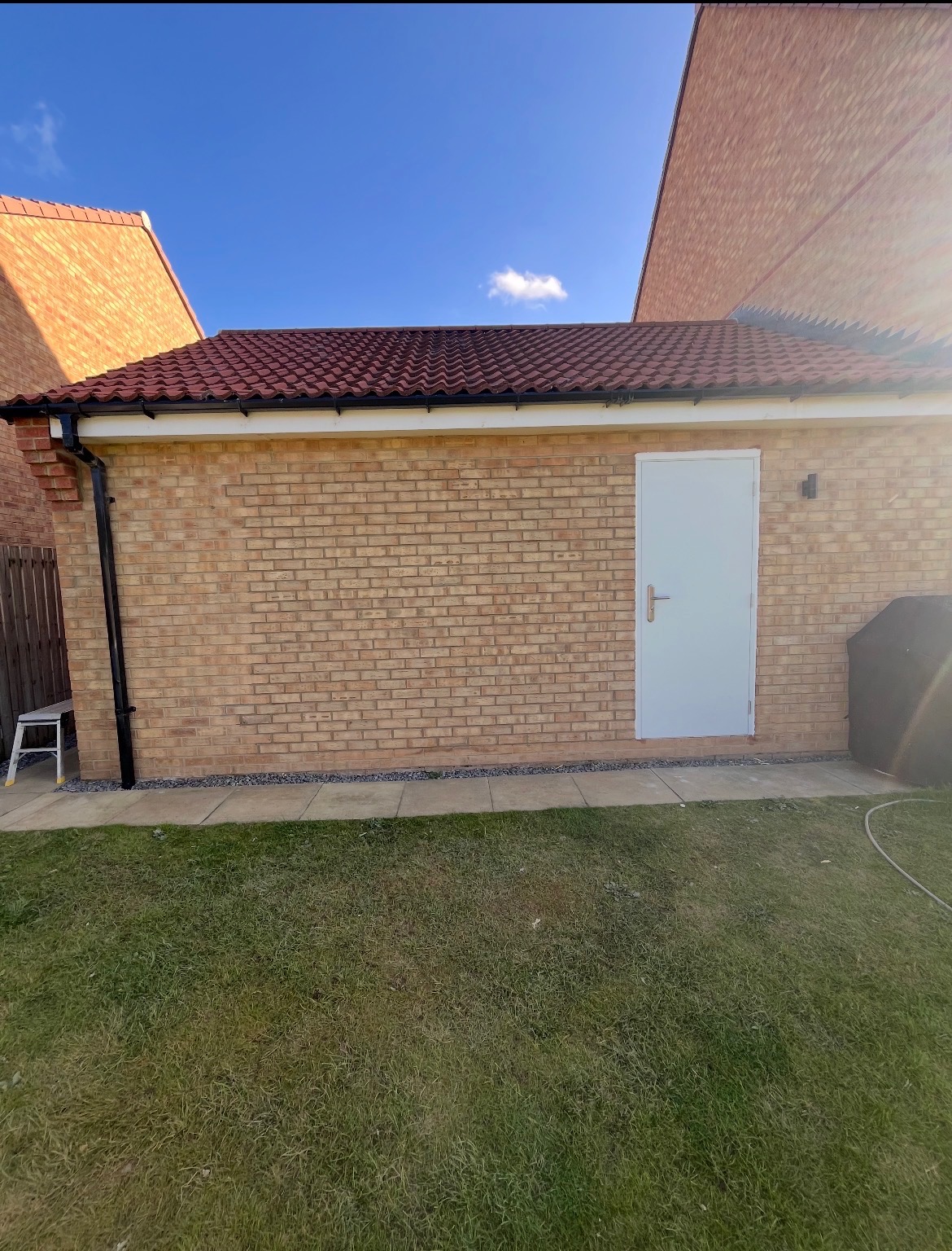 New brick garage wall with a tiled roof and white side door
