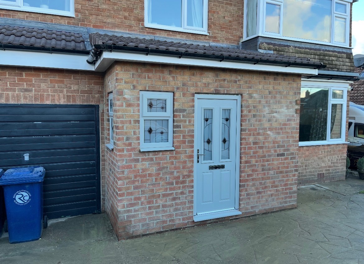Newly built brick front porch with a pale grey door, leaded windows and a tiled roof