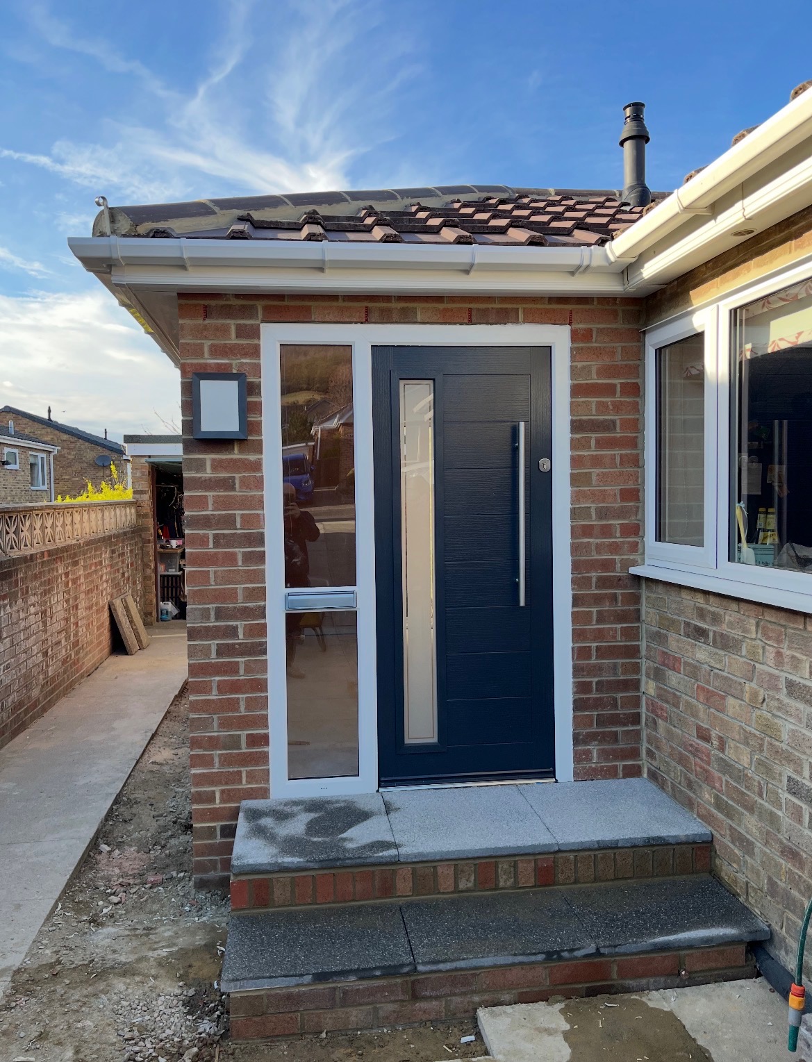Brick porch with a dark grey door and granite steps